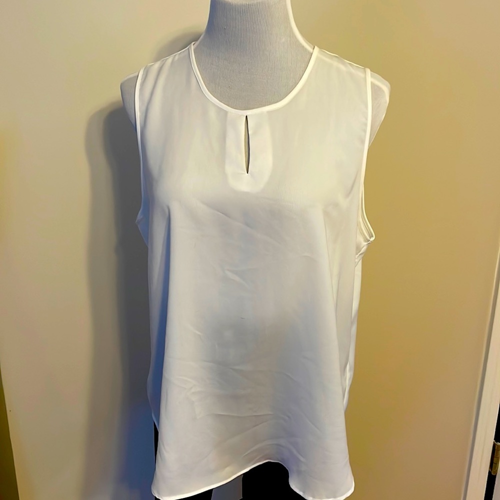 Cream sleeveless top with split front accent.